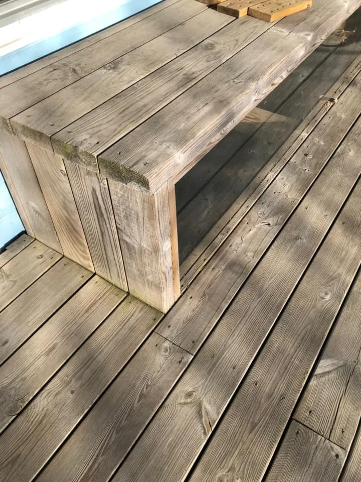 Inbyggd bänk i trall som täcker över ljusgård vid husväggen