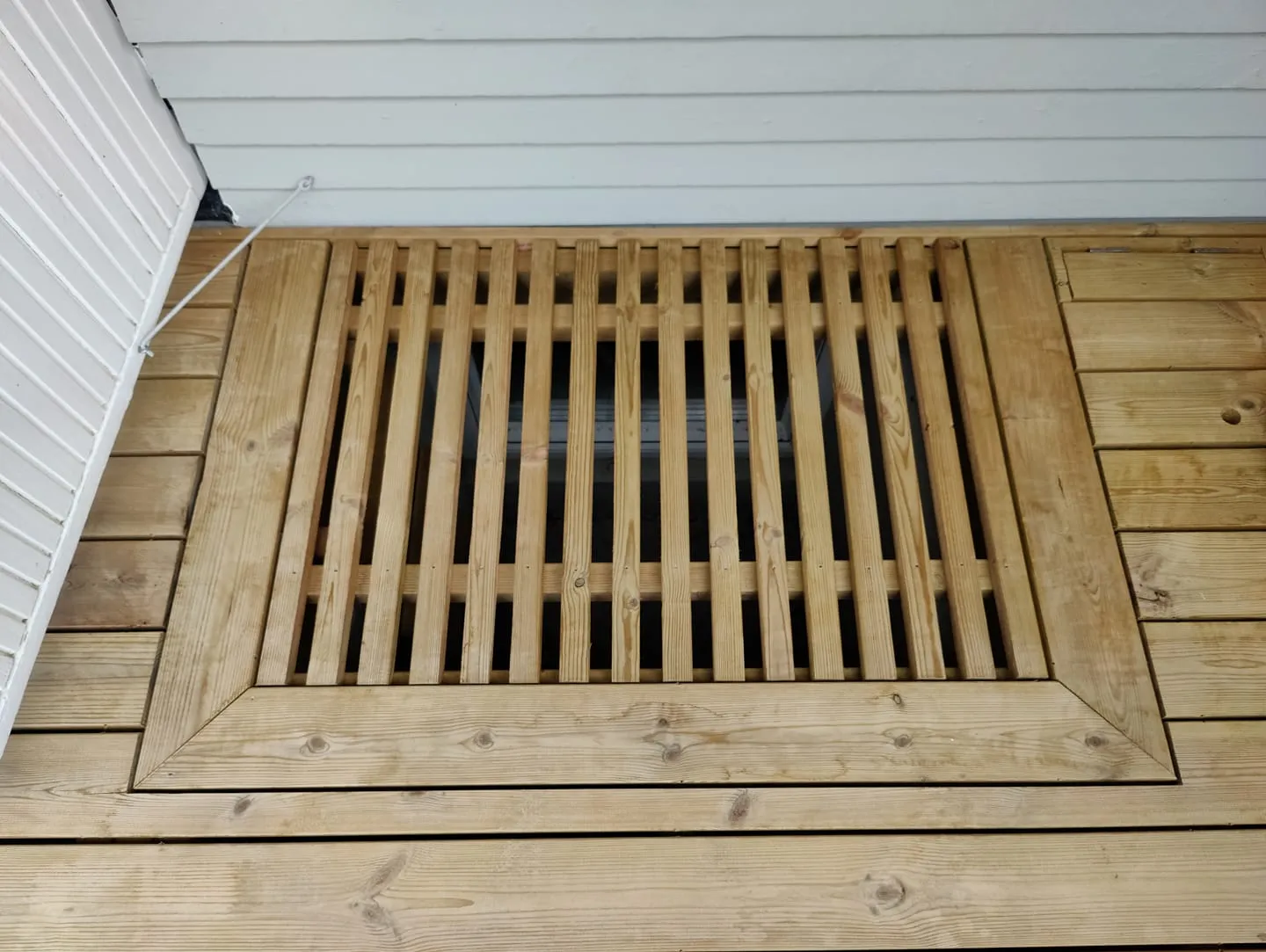 Trallgaller i träram över källarfönster, sett uppifrån