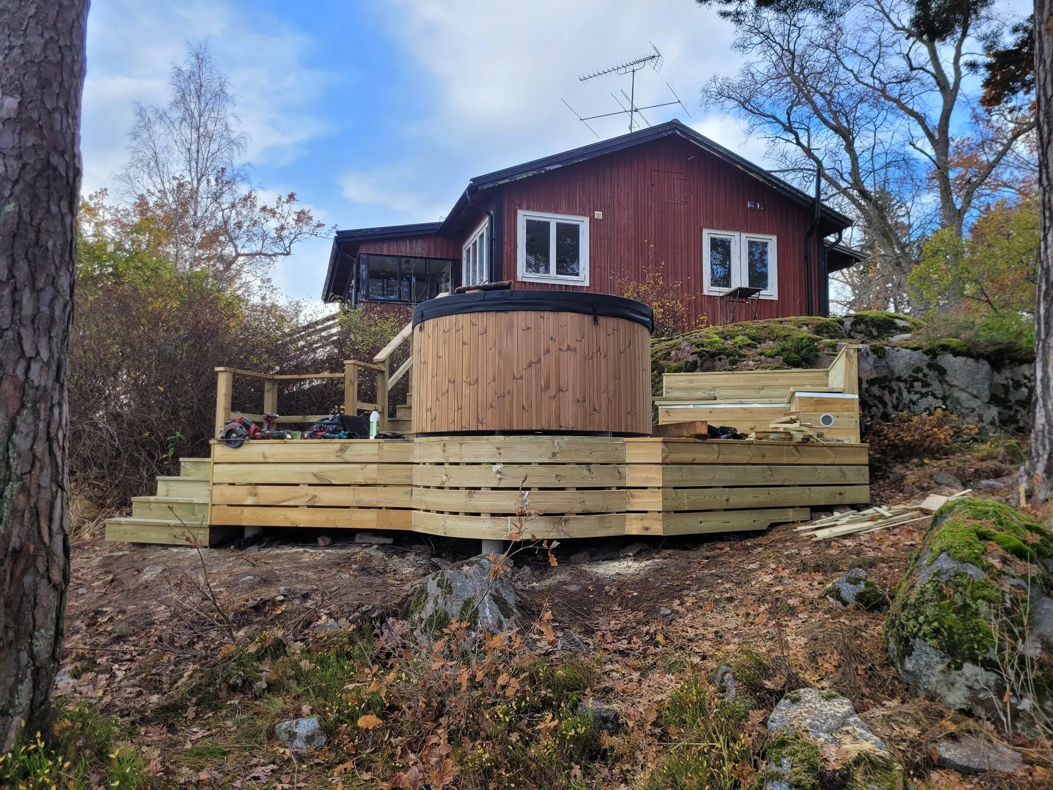 Altanen med badtunna sedd från sidan mot rött hus