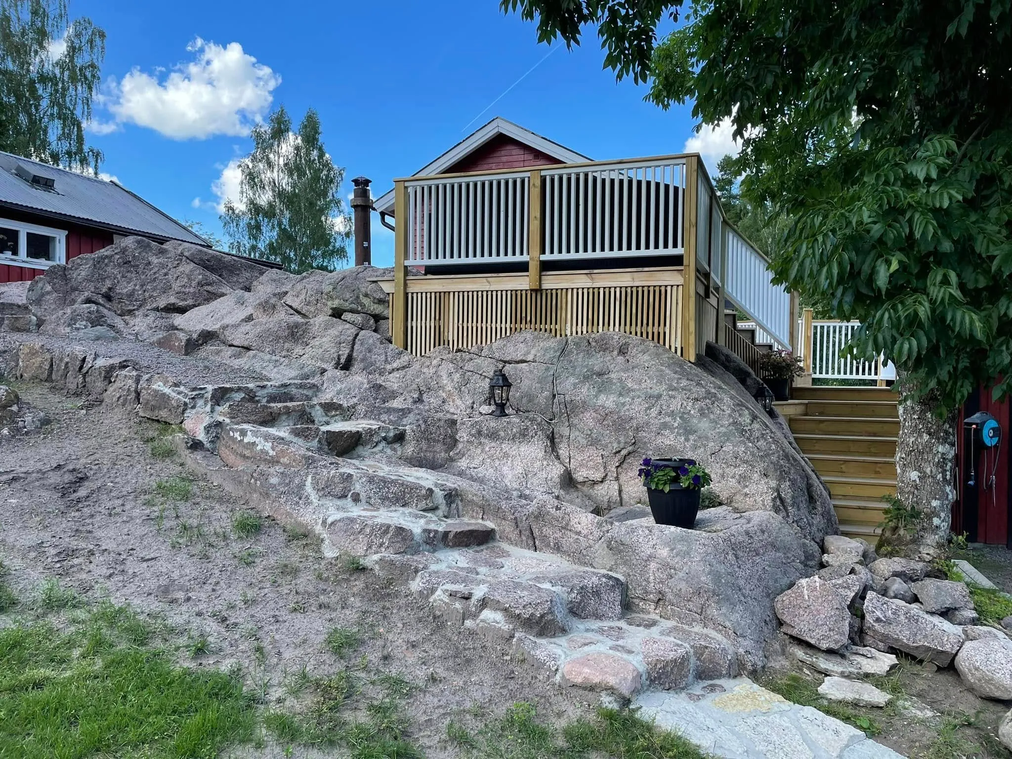 Altan på klippig tomt med stående vitt räcke och trappa