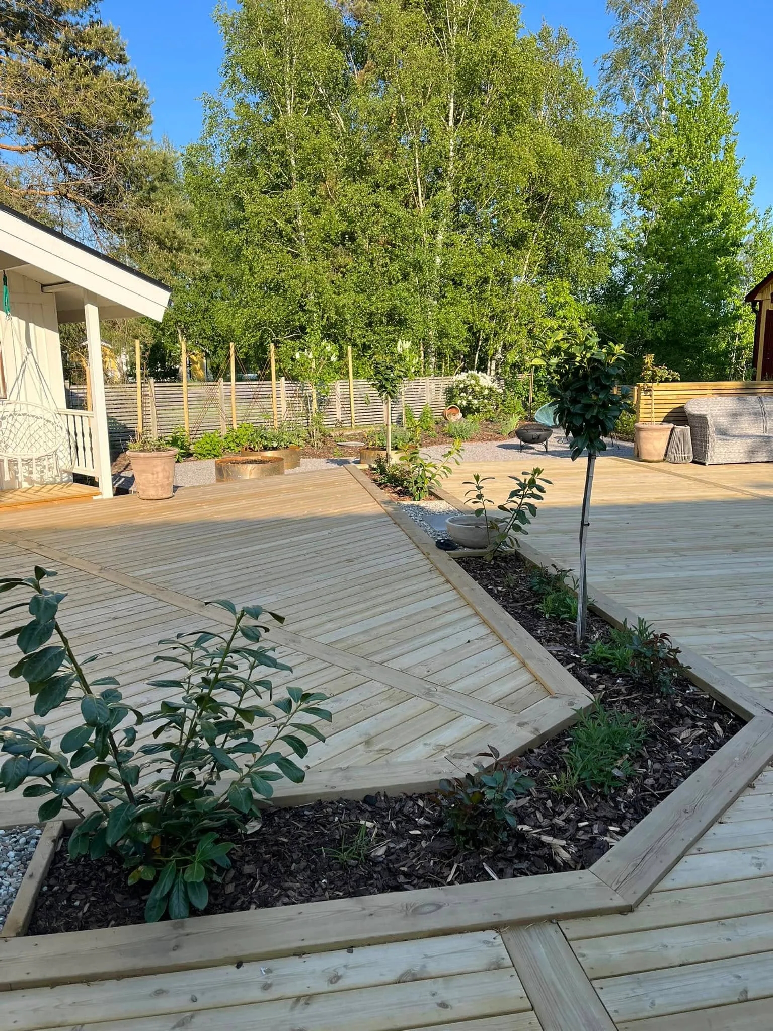 Trädäck med integrerade planteringslådor och grönska runtom