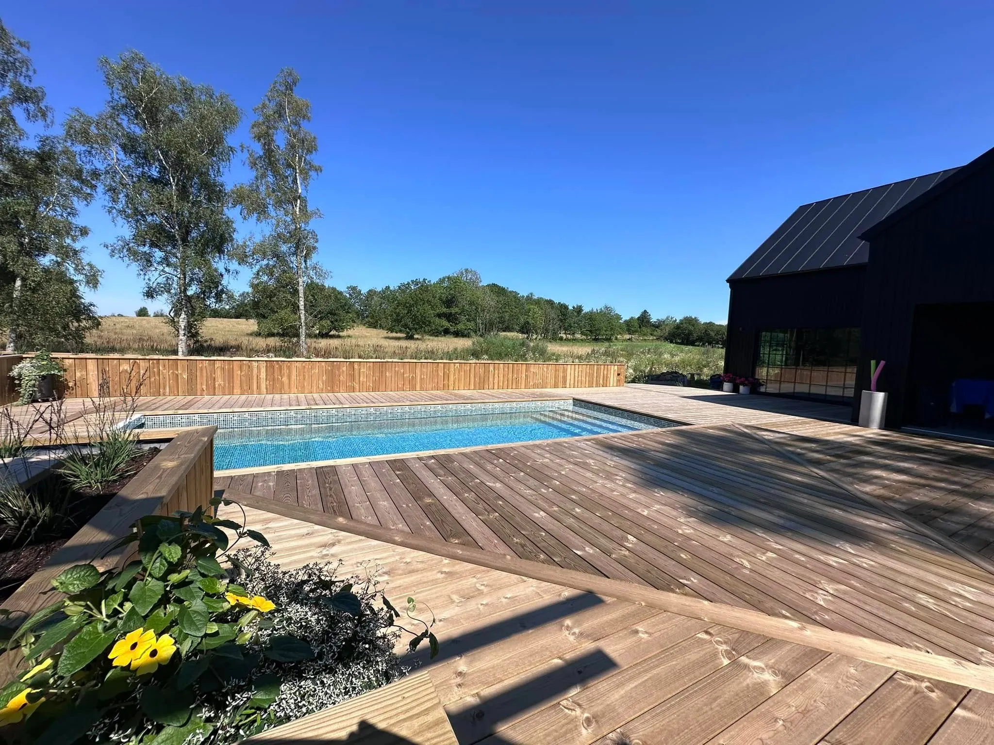 Rymlig poolaltan med rektangulär pool, integrerad planteringslåda och högt plankräcke