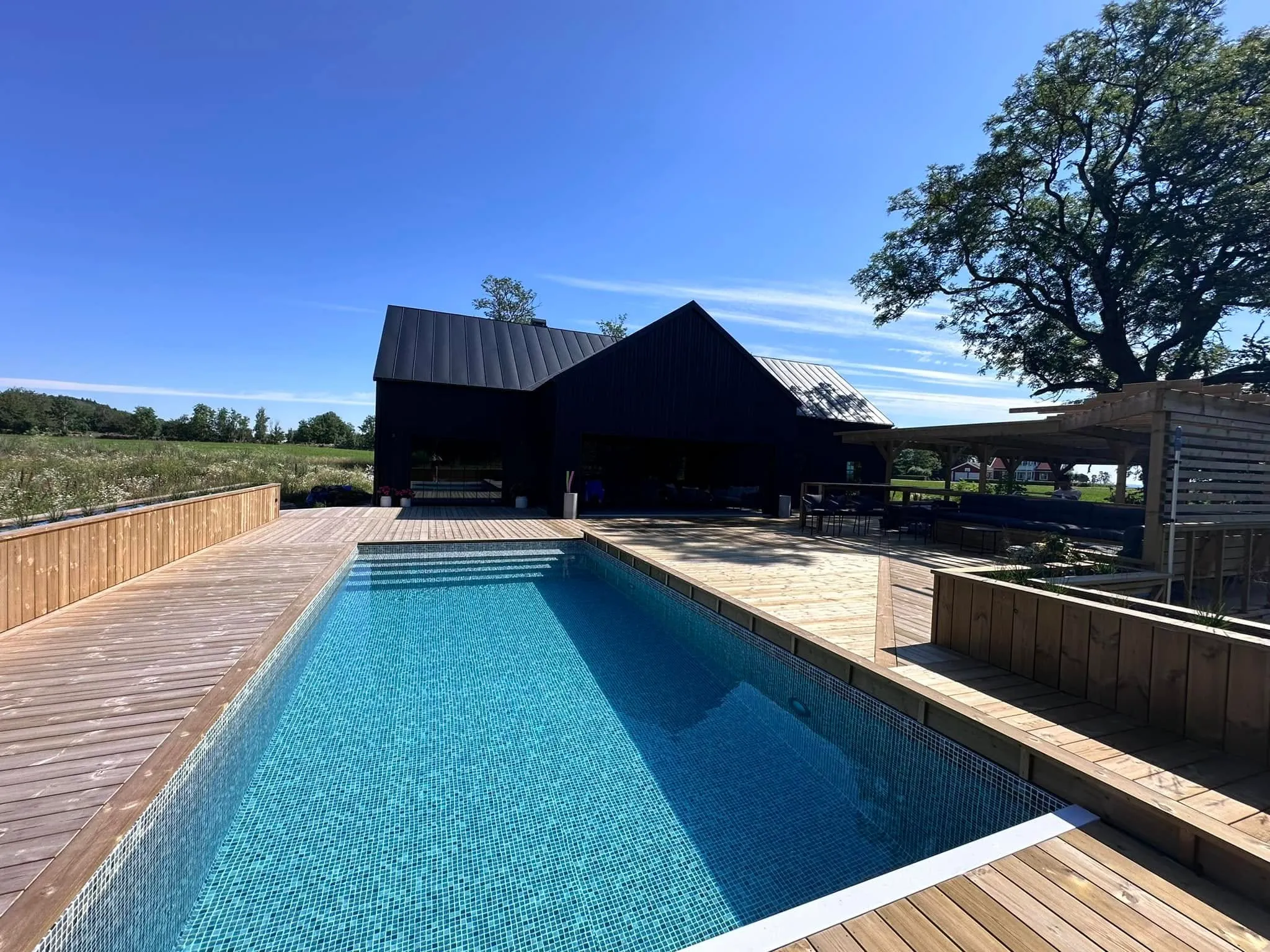 Poolen sedd från sidan med omgivande trädäck och pergola