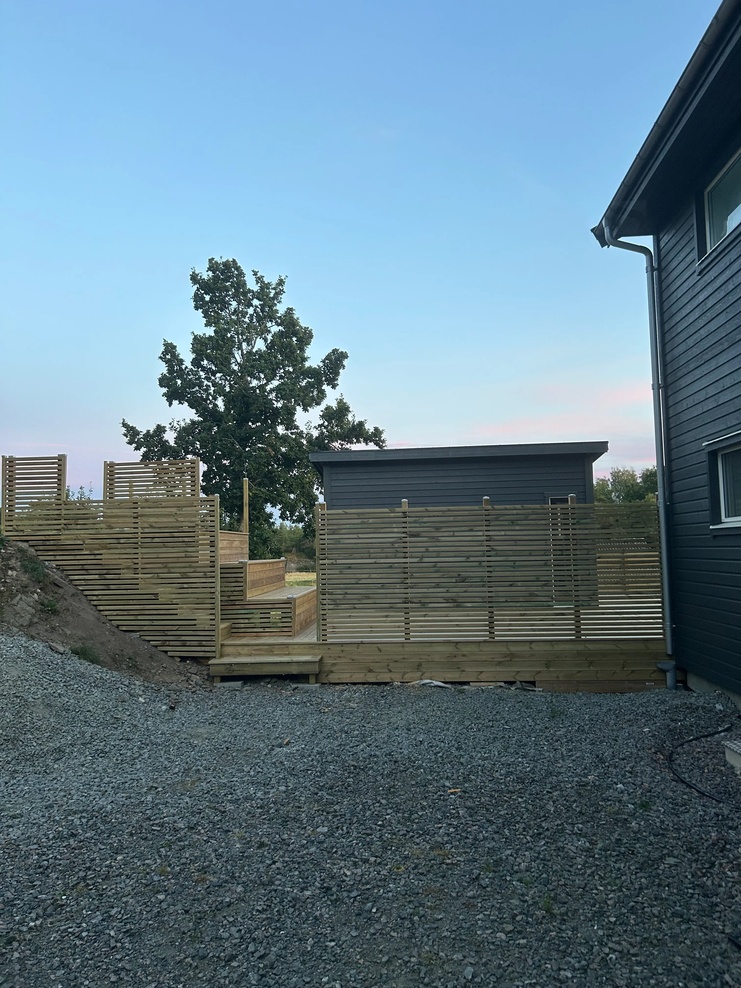 Christoffers färdigbyggda altan med staket och trappa mot trädgården