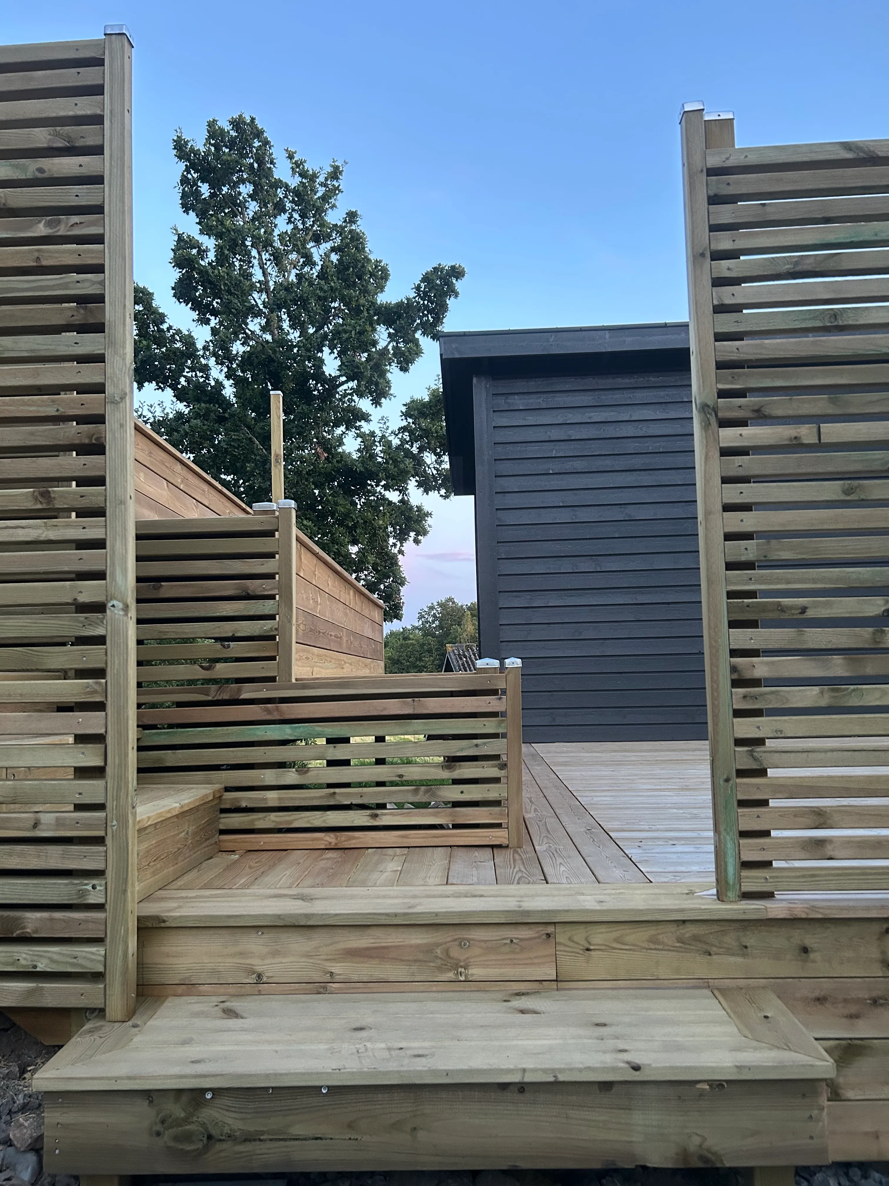 Altanen sedd från sidan med staket och trappa