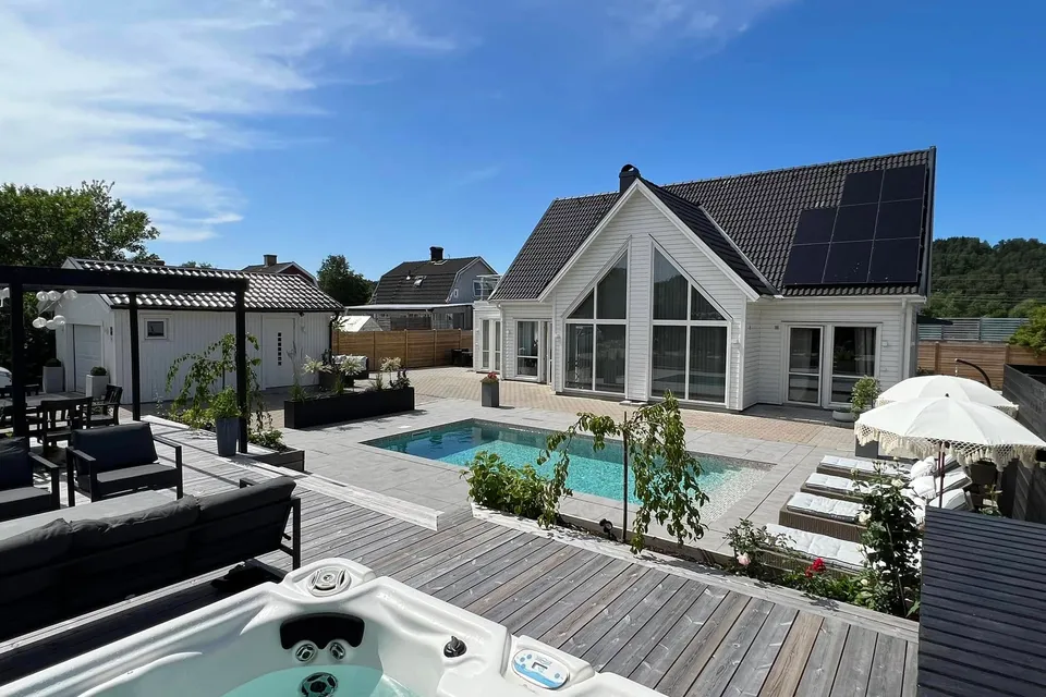 Modern vit villa med poolaltan, utomhusspa och trädäck i sommarsol