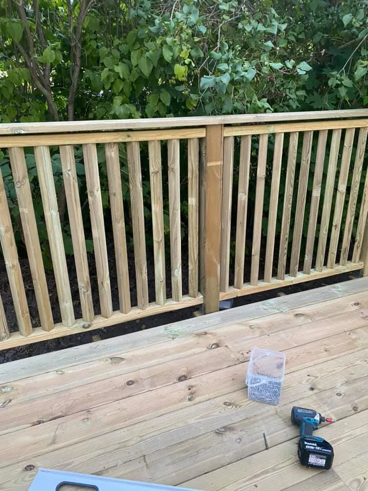 Stående trästaket med överliggare, tillverkat av tryckimpregnerat trä.