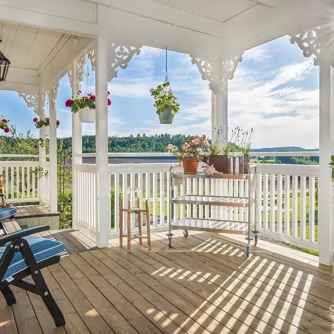 Vit veranda med stående räcke samt dekorativa detaljer.