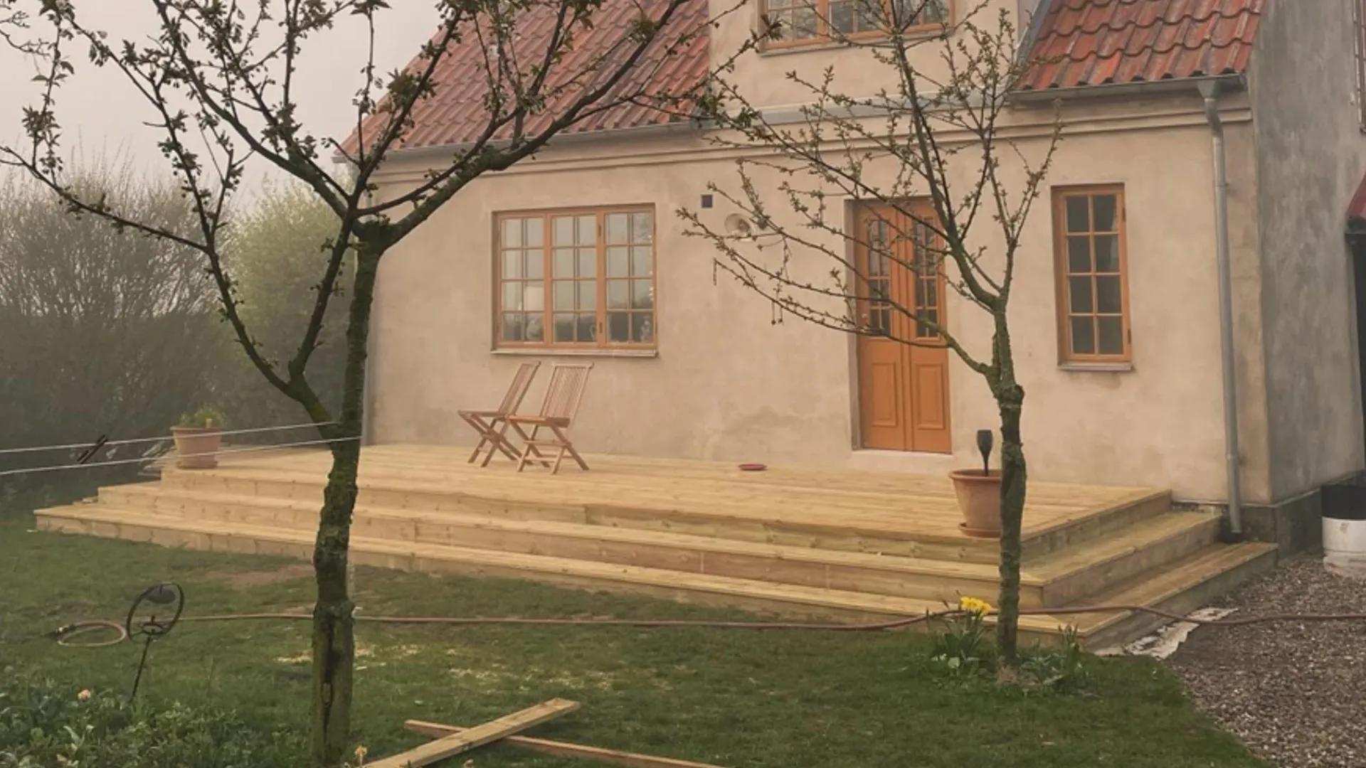 Stefan Wendins färdigbyggda altan med trappa runt ett putsat hus