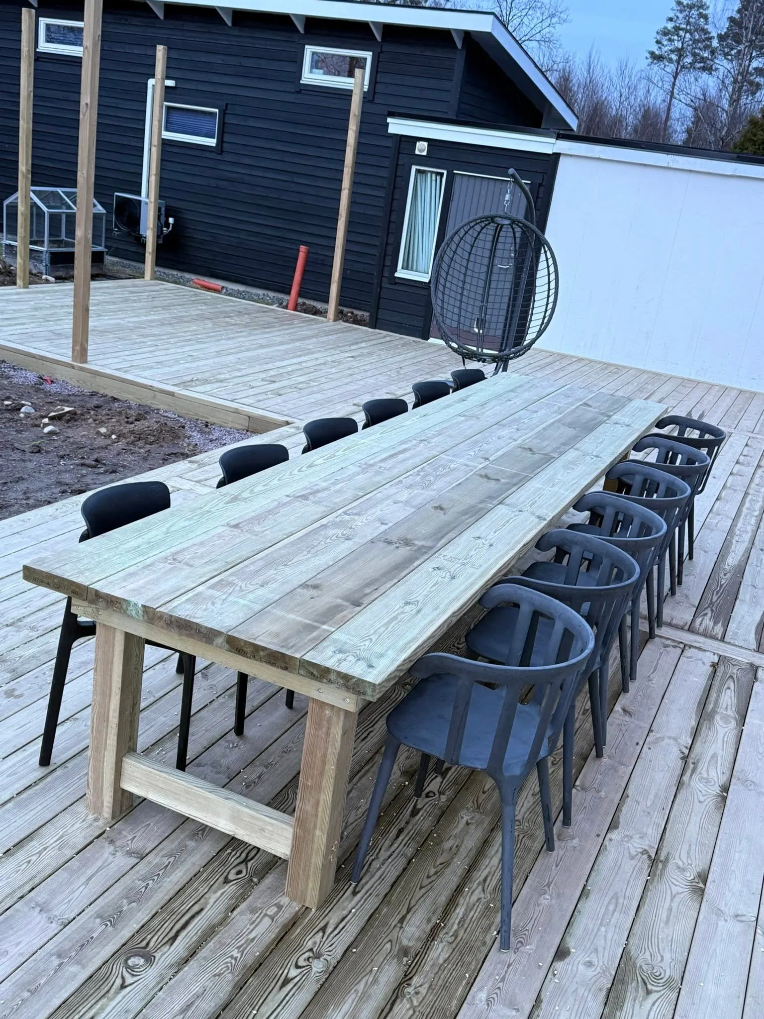 Stort hemmabyggt utebord sett från sidan med stolar runtom