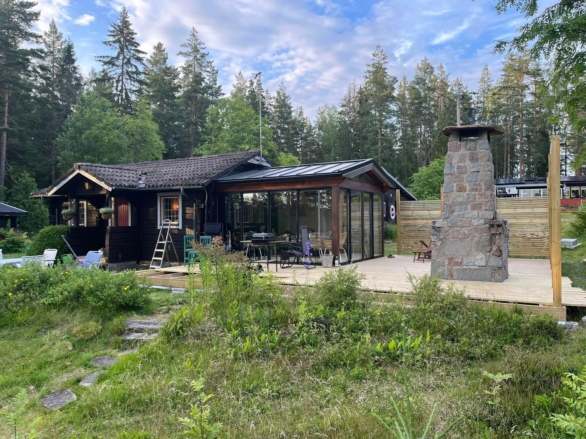 Torpets uterum med glaspartier och steneldstad sett från trädgården