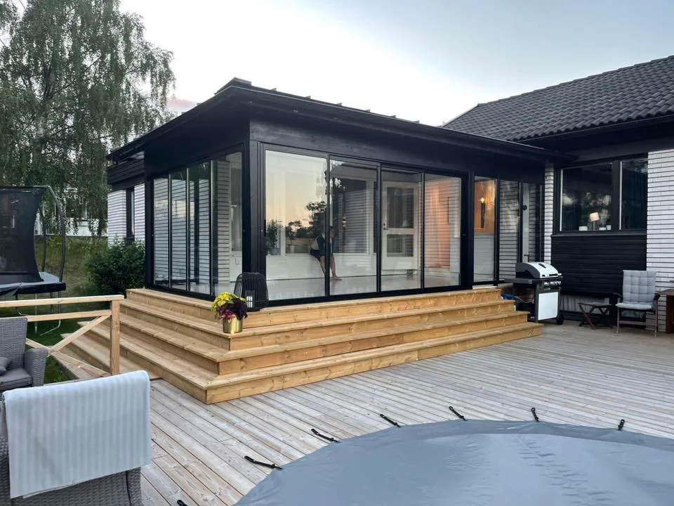 Modernt svart uterum med omgivande trädäck och trappa