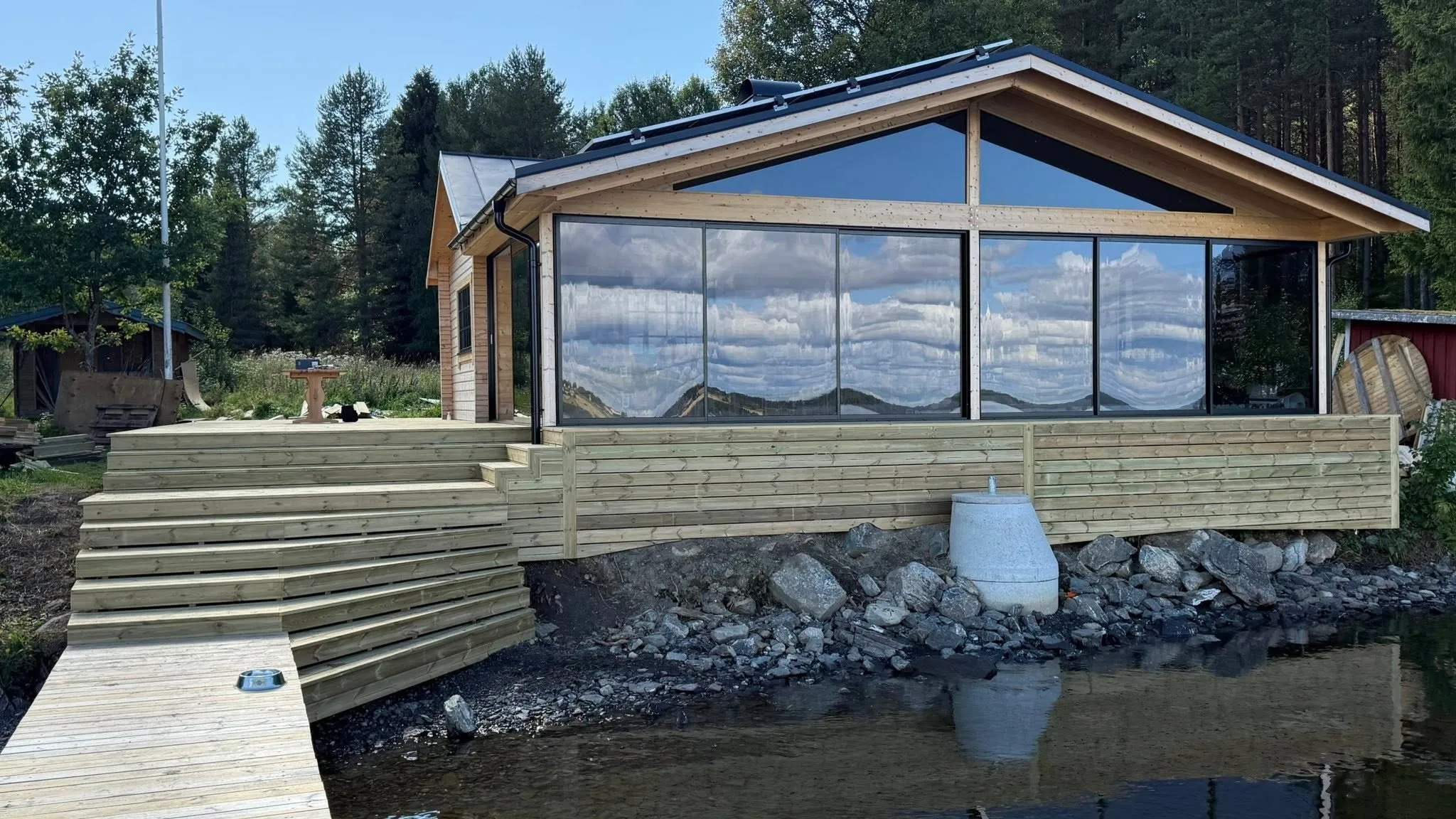 Uterummets trädäck vid sjön med glaspartier