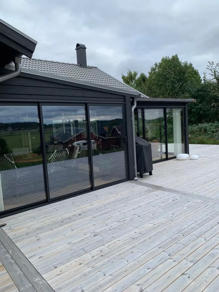 Uterummets exteriör med svarta glaspartier och trädäck