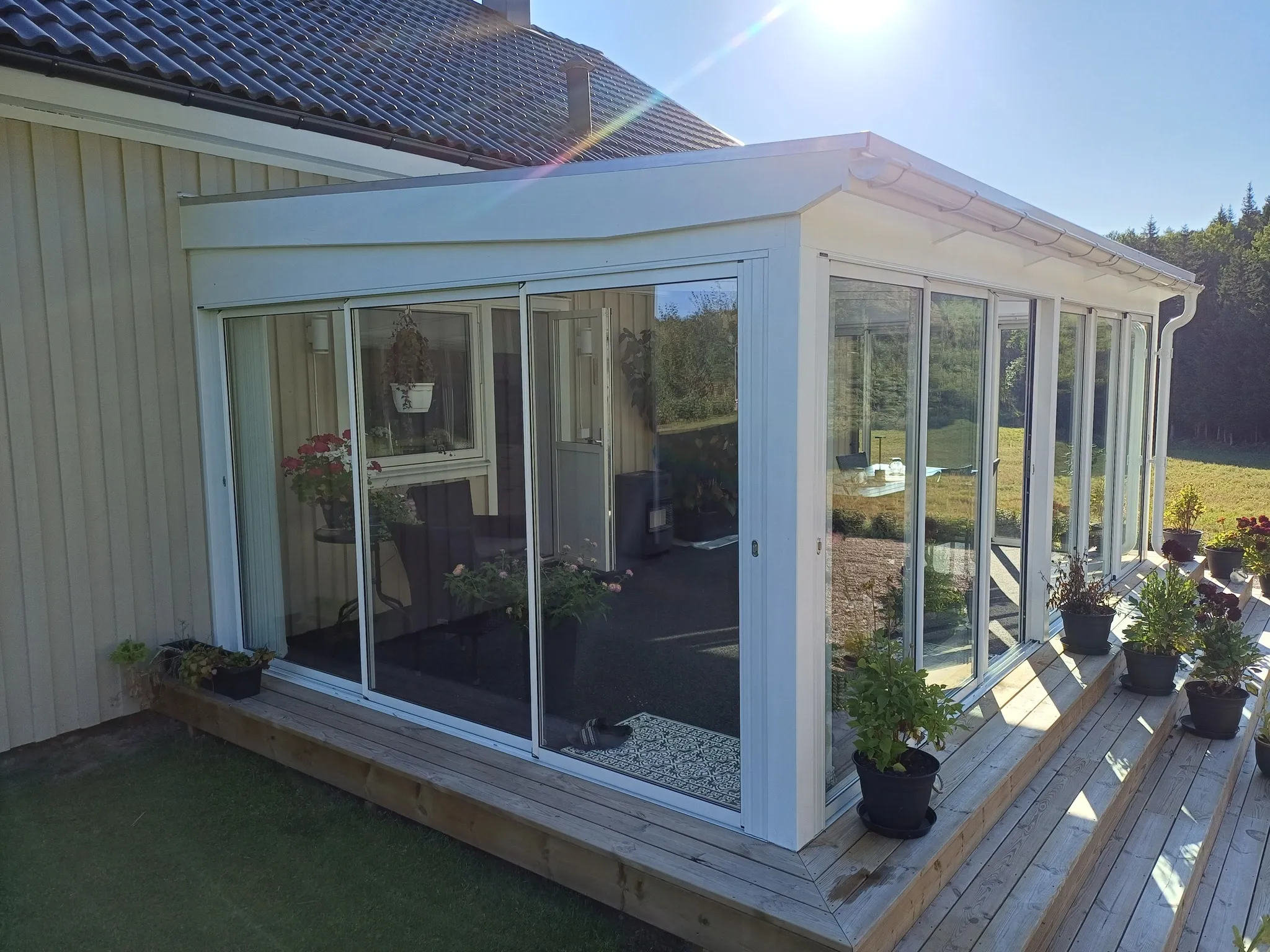 Klassiskt vitt uterum med blommor på gult trähus