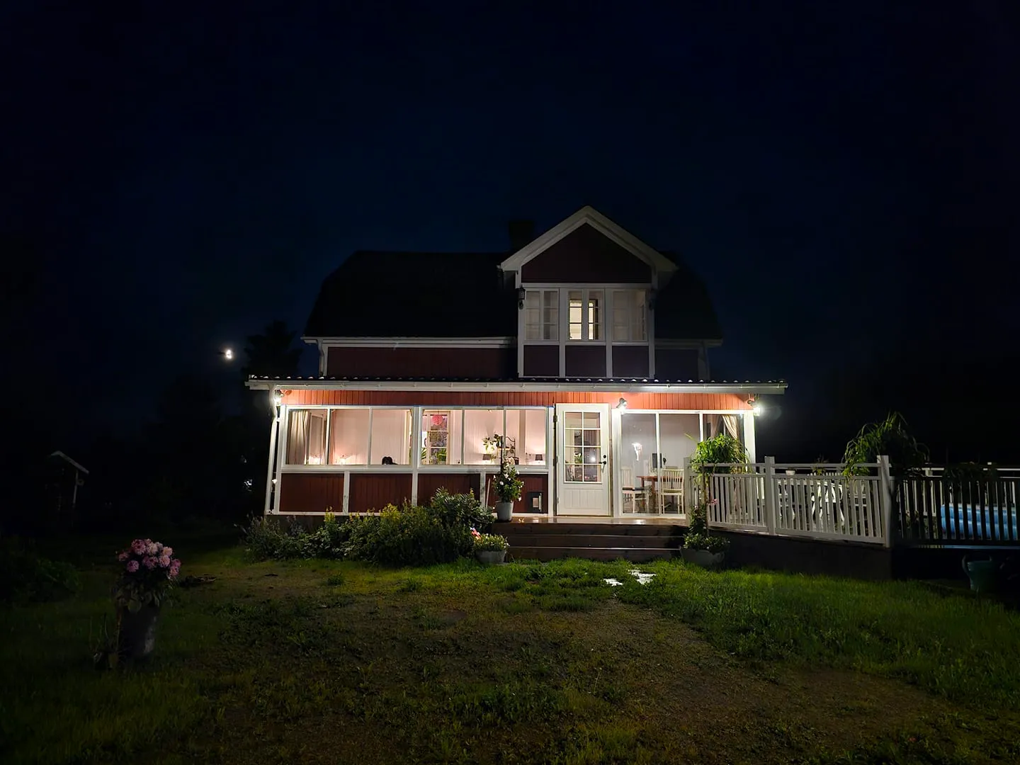 Rött svenskt hus med upplyst uterum på kvällen